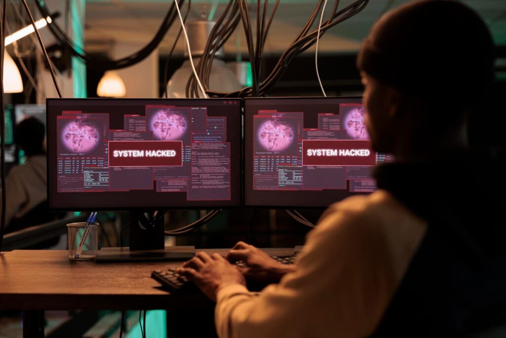 A woman in front of a two screens that show system hacked status